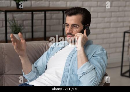 Young man in glasses talk on smartphone at home Stock Photo