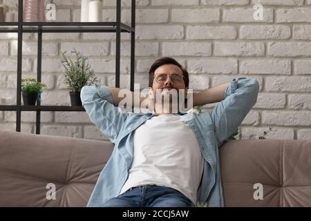 Calm young man relax on sofa at home sleeping Stock Photo
