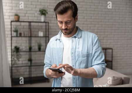 Young caucasian man browsing modern smartphone at home Stock Photo