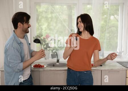 Excited millennial couple cook having fun together Stock Photo