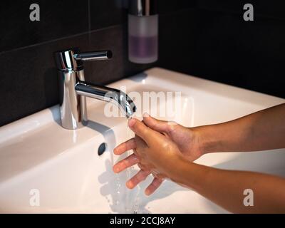 Hand washing personal hygiene boy washing hands rubbing soap for 20 seconds following steps, cleaning wrists and rinsing under water at home bathroom. Stock Photo