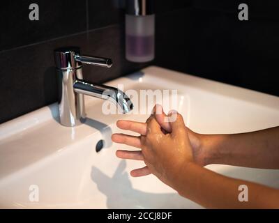 Hand washing personal hygiene boy washing hands rubbing soap for 20 seconds following steps, cleaning wrists and rinsing under water at home bathroom. Stock Photo