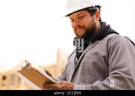 Portrait of architect drawing plan in notebook at construction site. Stock Photo