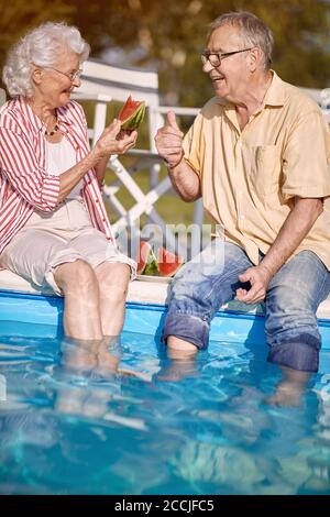 Romantic happy senior man and woman  enjoy on summer holiday near swimming pool and  eating watermelon. Stock Photo