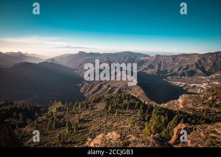 A panorama view of a sunset over the Roque Nublo in Gran Canaria, Spain. Tenerife is visible in the background. Stock Photo