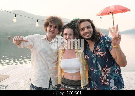 Portrait of group of friends embracing and smiling at camera while standing outdoors Stock Photo