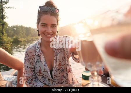 Happy young woman toasting with wine with her friends during party on the nature Stock Photo