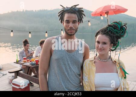 Portrait of young beautiful couple smiling at camera while spending time at a party on a pier Stock Photo