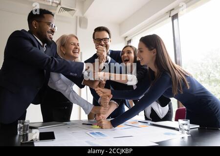 Happy employees coworkers stacking fists together showing corporate spirit Stock Photo