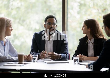 Troubled dark-skinned ceo informing staff about hard times in business Stock Photo