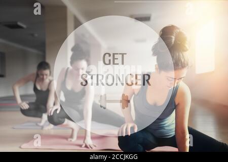 A group of young women doing yoga in the classroom. The concept of sports, aerobics and yoga practice. Tint. Text GET STRONGER. Stock Photo
