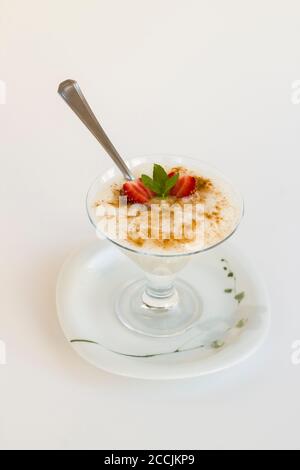 Traditional Turkish Rice Puding in stylish glass bowl with spoon on white background. Stock Photo