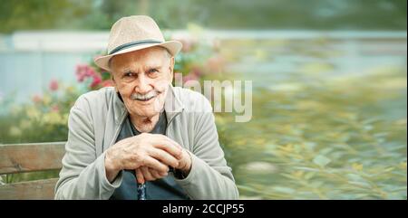 Portrait of a smiling and confident senior 87 years old cute in a hat with a mustache. Happy active old age. Stock Photo