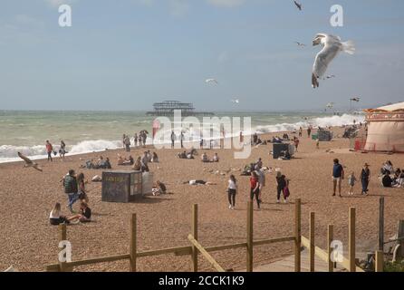 People on the beach in Brighton, East Sussex, UK with rough seas and the Western pier in the background Stock Photo