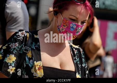Young woman wearing patterned fabric face covering in street, London, UK Stock Photo