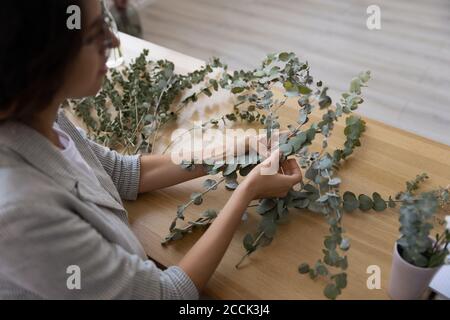 Focused young female florist creating handmade house interior decorations. Stock Photo