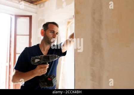 Construction worker using drill at a wall Stock Photo
