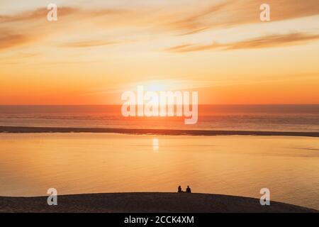 Silhouette couple watching sunset at Atlantic ocean, Dune of Pilat, Nouvelle-Aquitaine, France Stock Photo