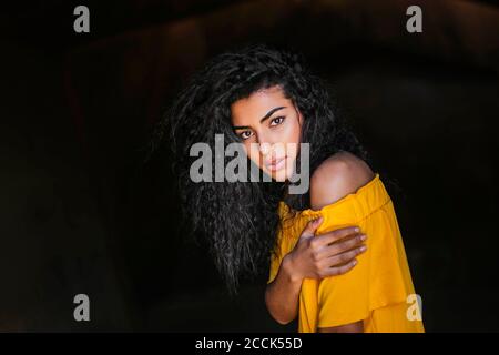 Portrait of young black-haired woman, dark background Stock Photo
