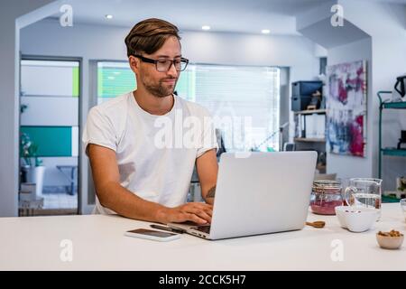 Male student using laptop at kitchen island in cooking class Stock Photo