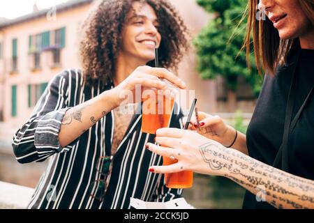 Close-up of happy couple toasting drinks while having fun in city Stock Photo