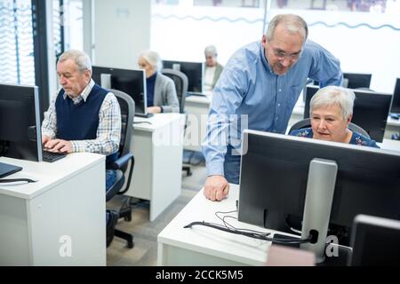 Active seniors attending computer course, intructor giving advice Stock Photo