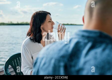 Young woman drinking glass of water at a lake Stock Photo
