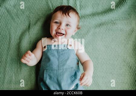 Close-up of cute baby girl laughing while lying on blanket at home Stock Photo