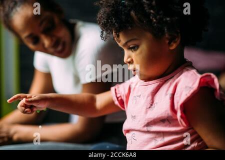 Close-up of baby girl with mother on bed at home Stock Photo