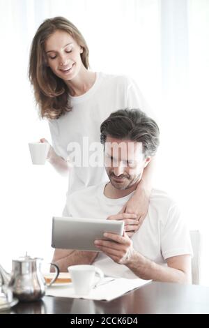 Couple having breakfast at home and using tablet Stock Photo