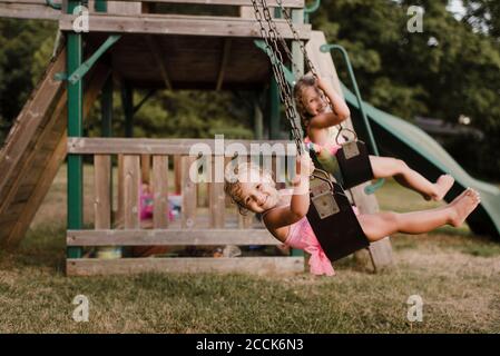 Happy girls with wet hair on a swing Stock Photo