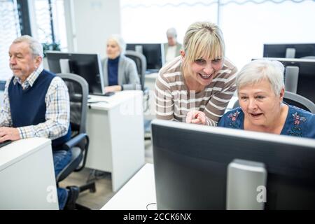 Active seniors attending computer course, intructor giving advice Stock Photo