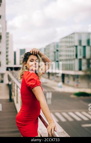 Beautiful young woman standing at bridge railing outdoors Stock Photo