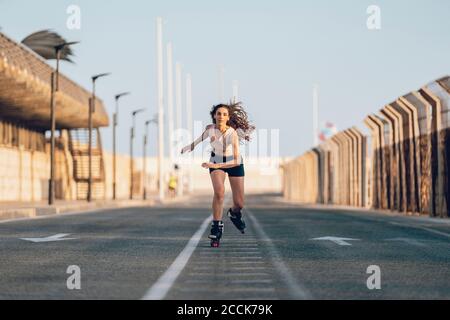 Young woman inline skating on boardwalk at the coast Stock Photo