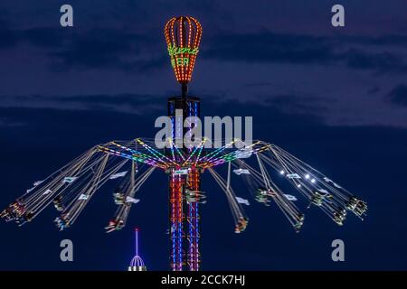 Germany, Bavaria, Munich, Aerial view of illuminated chain swing ride spinning against sky at night Stock Photo