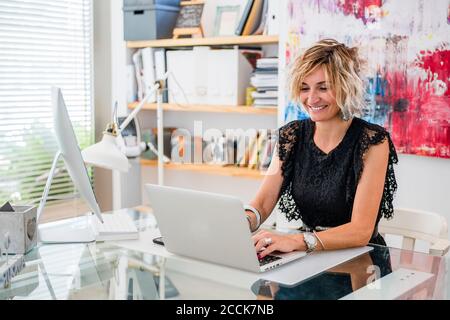 Smiling female instructor using laptop on table in cooking school Stock Photo