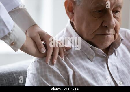 Compassionate young female doctor supporting depressed old retired patient. Stock Photo