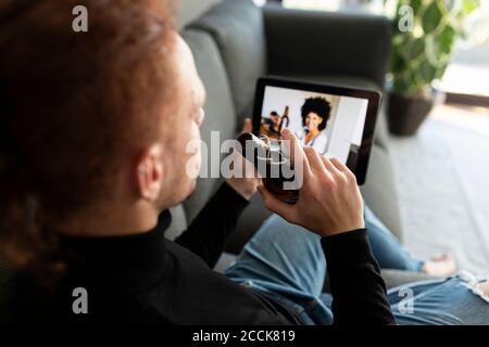 Man using digital tablet while drinking beer at home Stock Photo