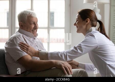 Smiling young kind female doctor supporting happy old 80s patient. Stock Photo