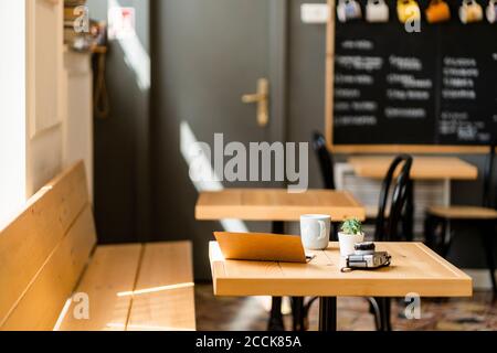 Book and camera on wooden table in modern coffee shop Stock Photo