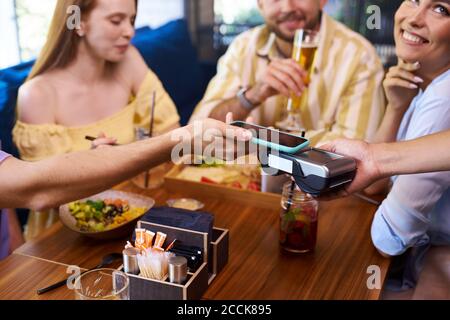 clients pay for meal via smartphone, in restaurant. contactless payment concept Stock Photo