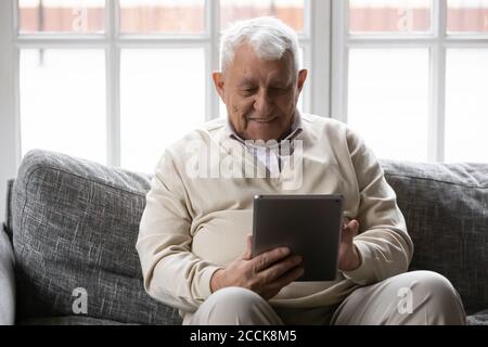Smiling older male pensioner using digital computer tablet. Stock Photo