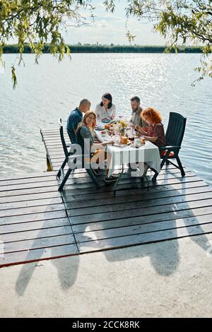 Friends having dinner on jetty at a lake Stock Photo