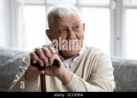 Smiling old disabled man resting on cozy couch. Stock Photo
