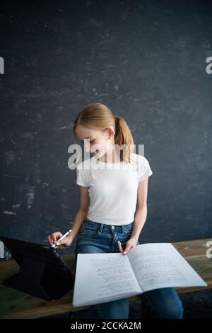 Blond girl learning and using tablet at home Stock Photo