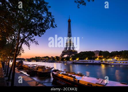 Eiffel Tower by Seine river against clear blue sky at sunset, Paris, France Stock Photo