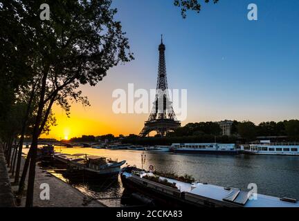 Eiffel Tower by Seine river against clear blue sky during sunrise, Paris, France Stock Photo
