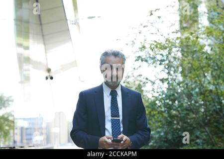 Businessman texting through smart phone in city Stock Photo