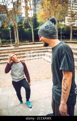 Side view of smiling male with friend standing in park Stock Photo