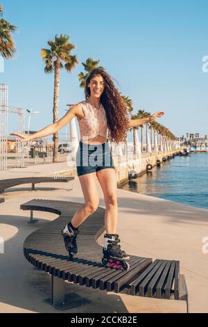 Young woman inline skating on bench Stock Photo